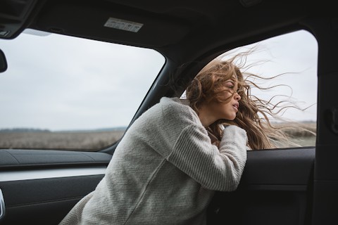 A woman with her head sticking out of an open car window
