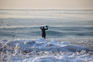 Cow Bay, Nova Scotia, showcasing a surfer riding a wave in the winter, highlighting the province's unique winter surfing scene.