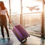 Woman walking through airport dragging suitcase, looking apprehensive, wondering if it's safe to travel after tooth extraction